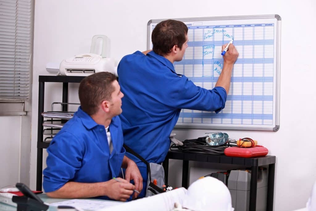 Two men scheduling service on a white board